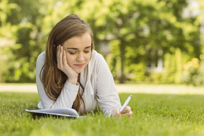 girl outside on grass reading a book